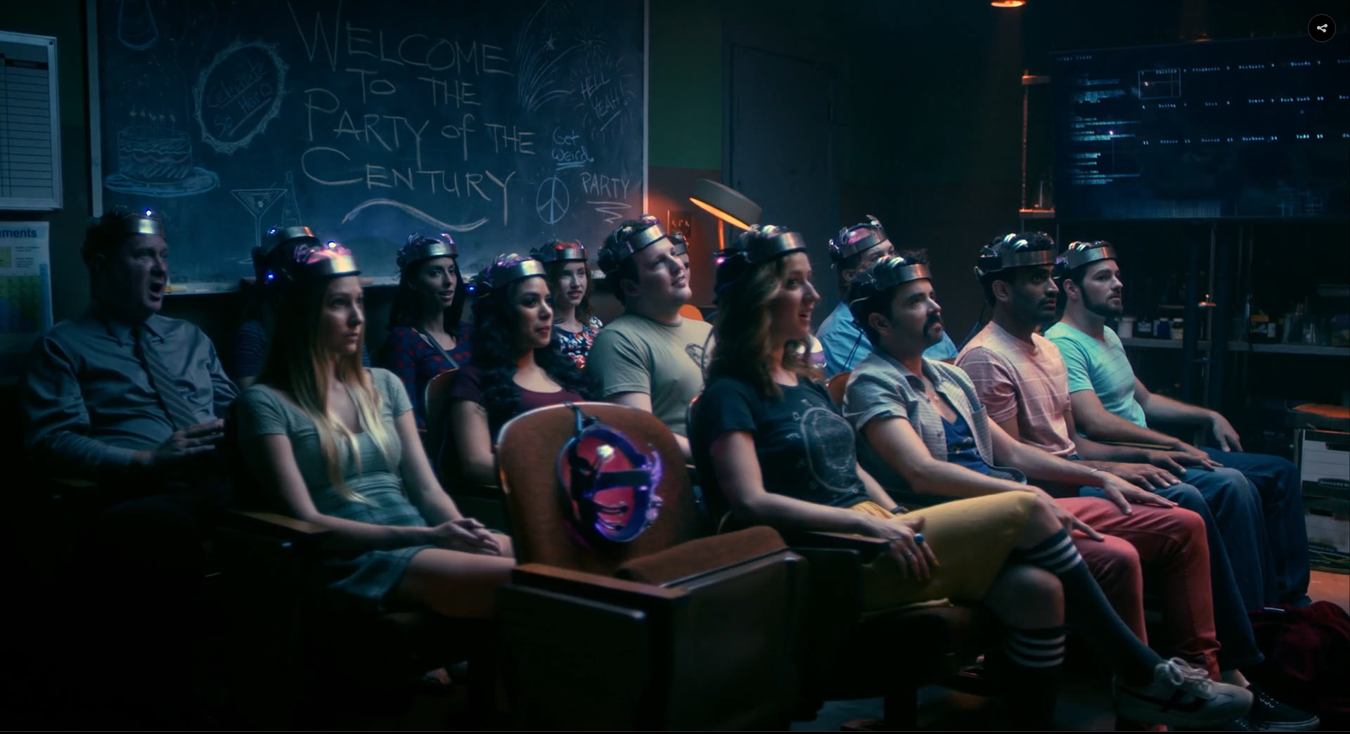 The Party of the Century scene: the Lab redressed with old theatre seating, around fourteen partygoers wearing the brain-interface headsets, and a chalkboard reading WELCOME TO THE PARTY OF THE CENTURY, Get Weird, Celebrate So Hard.