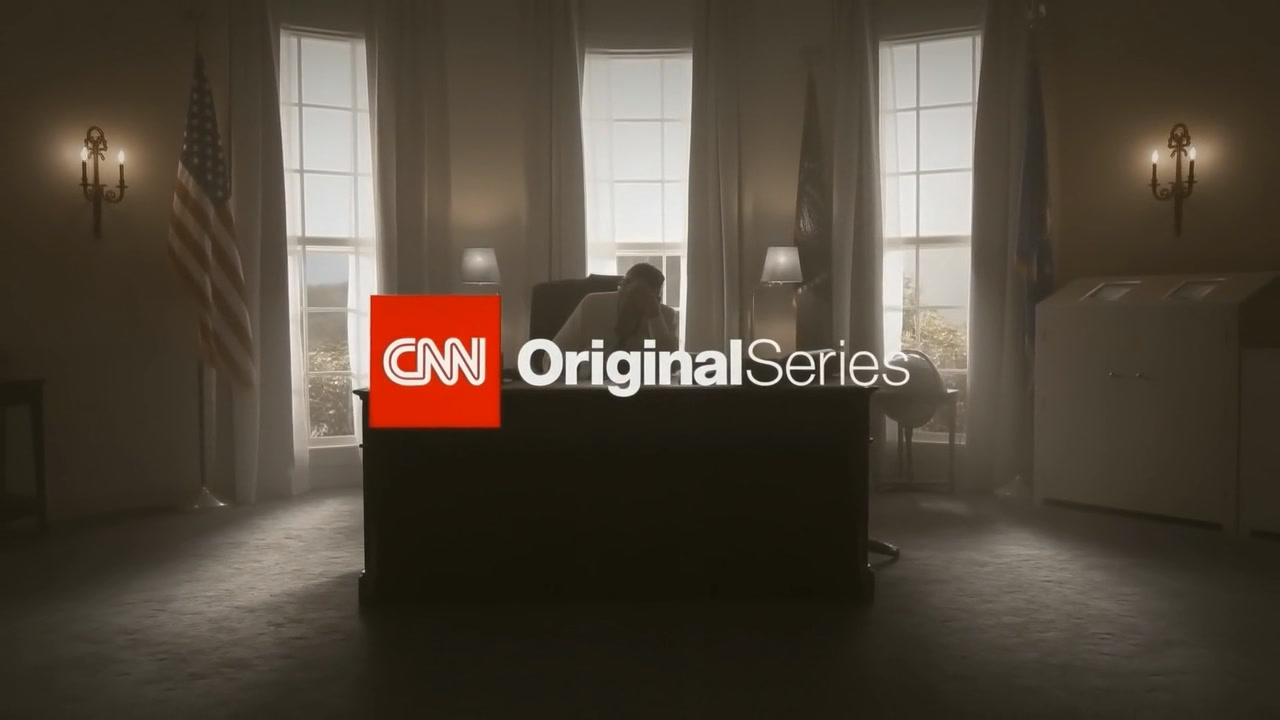 A frame from the series: the Oval Office set in low light, the president at the desk between three backlit windows with flags and wall sconces, under the CNN Original Series mark.