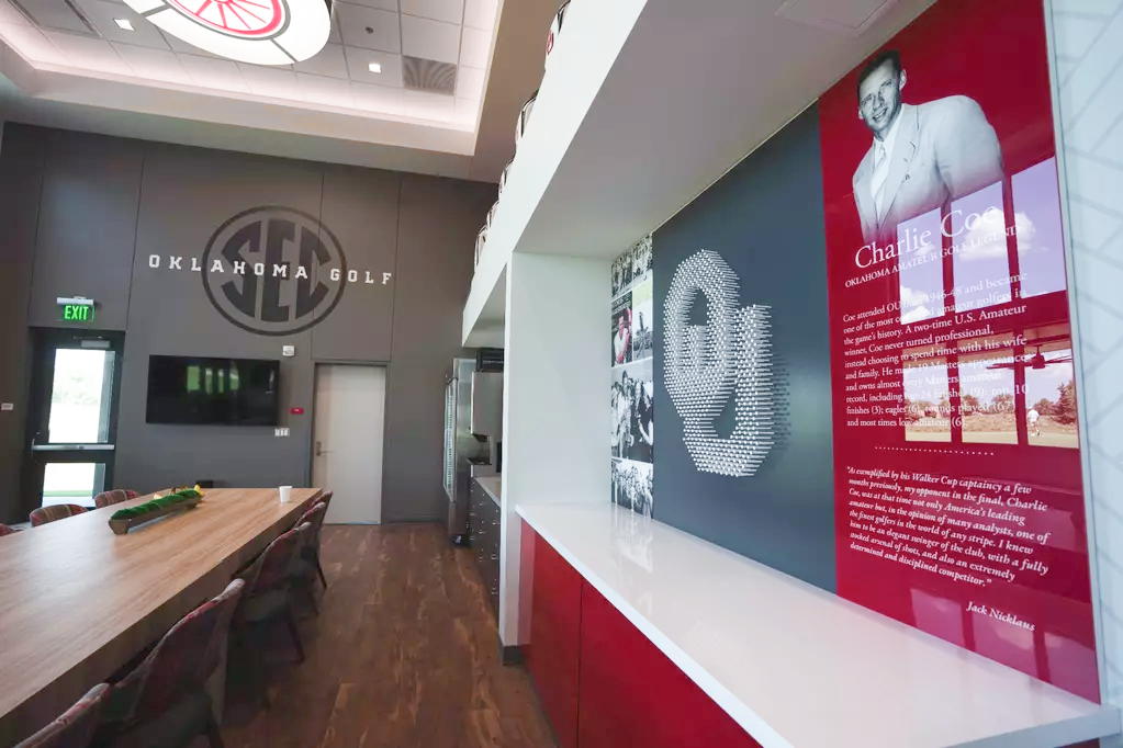 Charlie Coe heritage wall, close: an OU monogram built from white golf tees on a gray ground, a black-and-white photo collage, and a red bio panel naming Coe an Oklahoma amateur legend.