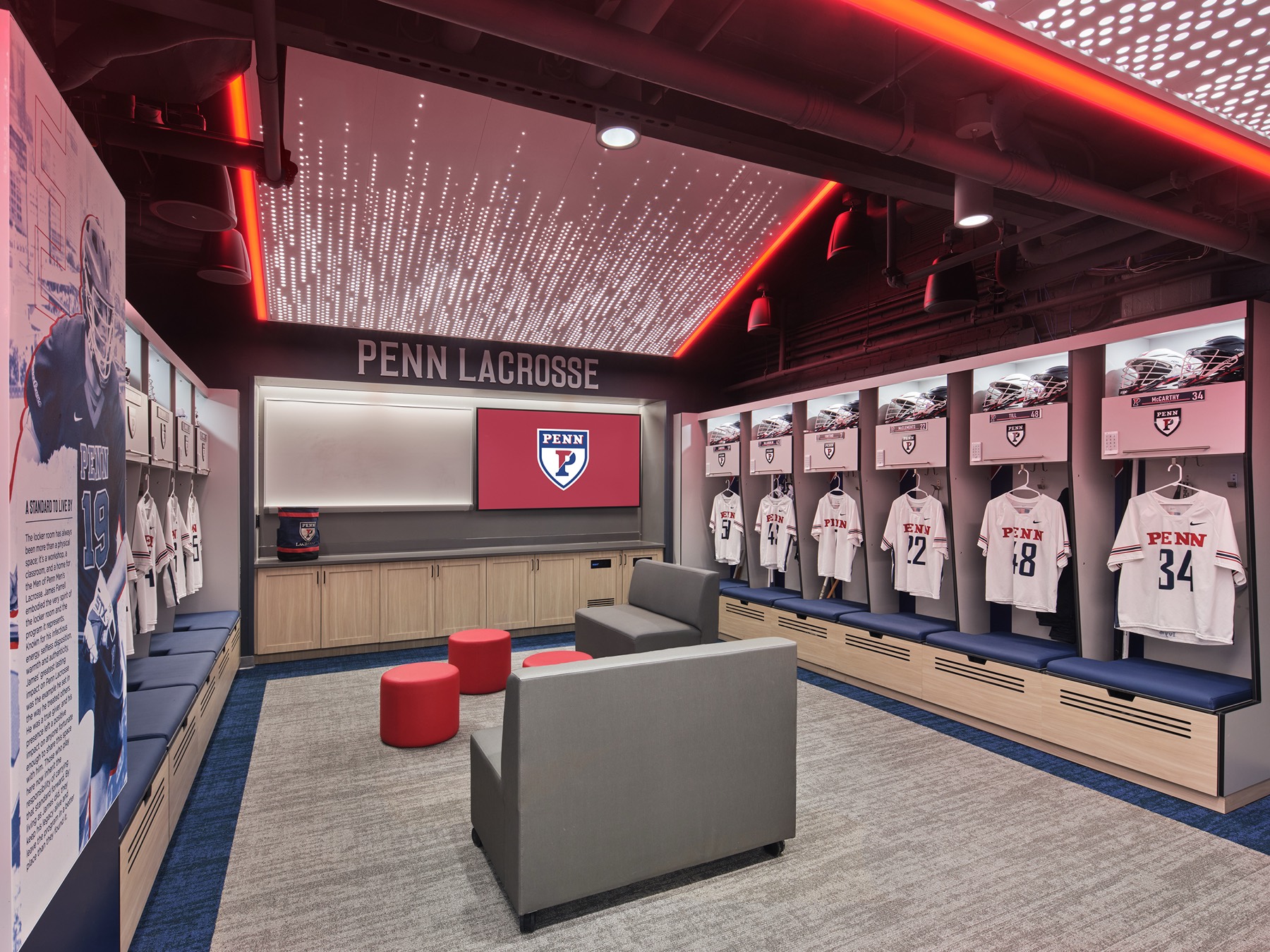 Wood-backed lockers with hanging jerseys under a PENN LACROSSE sign; a monitor with the Penn shield over built-in cabinets, red-lit ceiling edge above a field of perforated light.